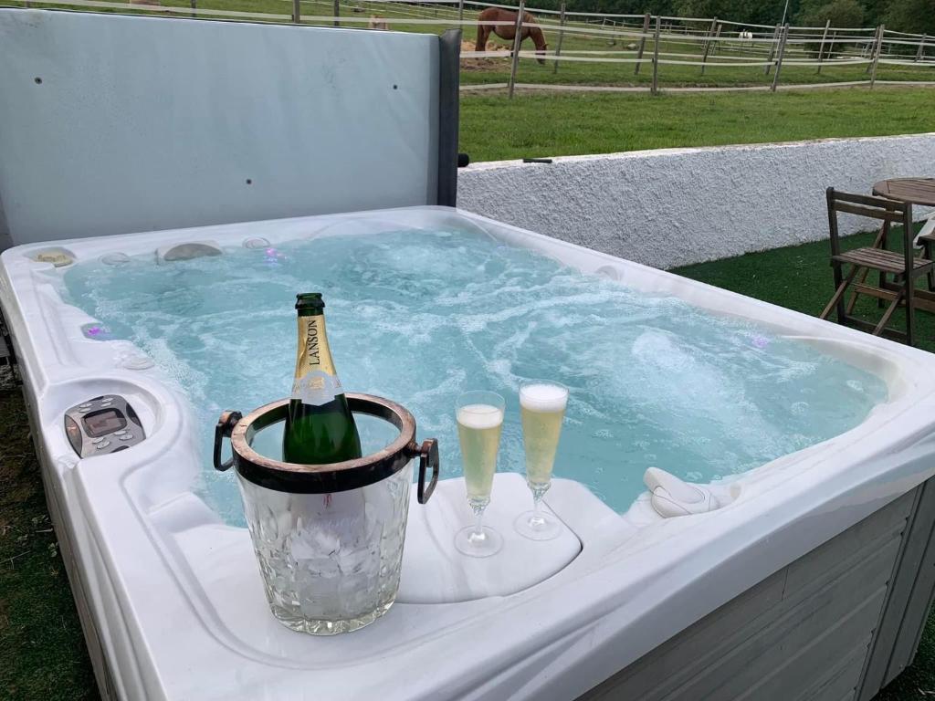 een hot tub met een fles champagne en 2 glazen bij Domaine du cheval d’argent 