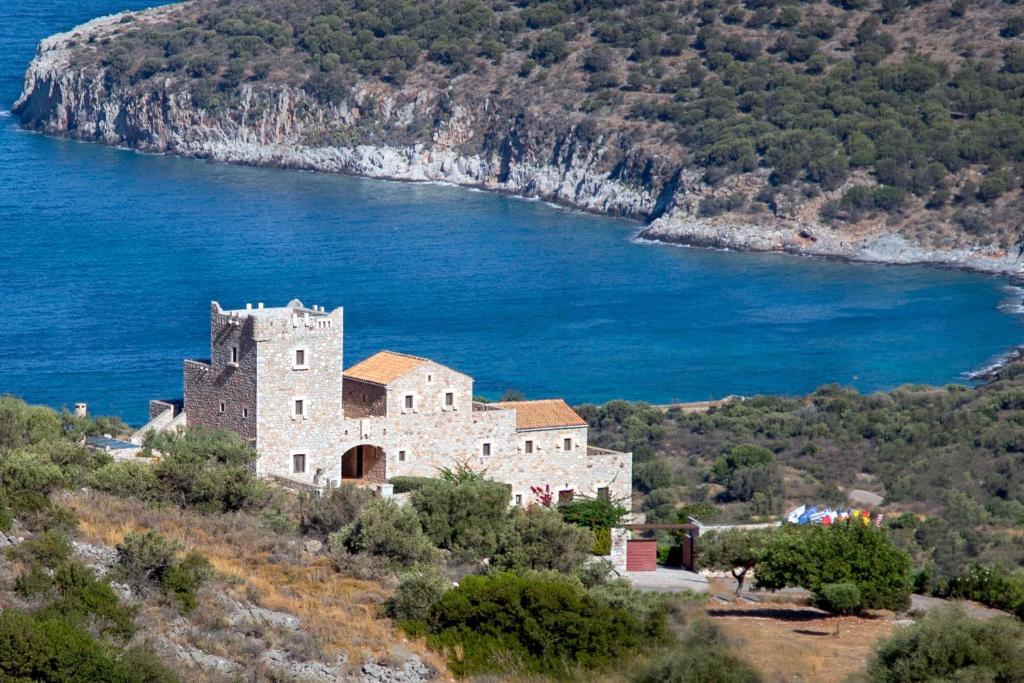 un vecchio edificio su una collina vicino a un corpo d'acqua di Focalion Castle Luxury Suites a Pyrgos Dirou