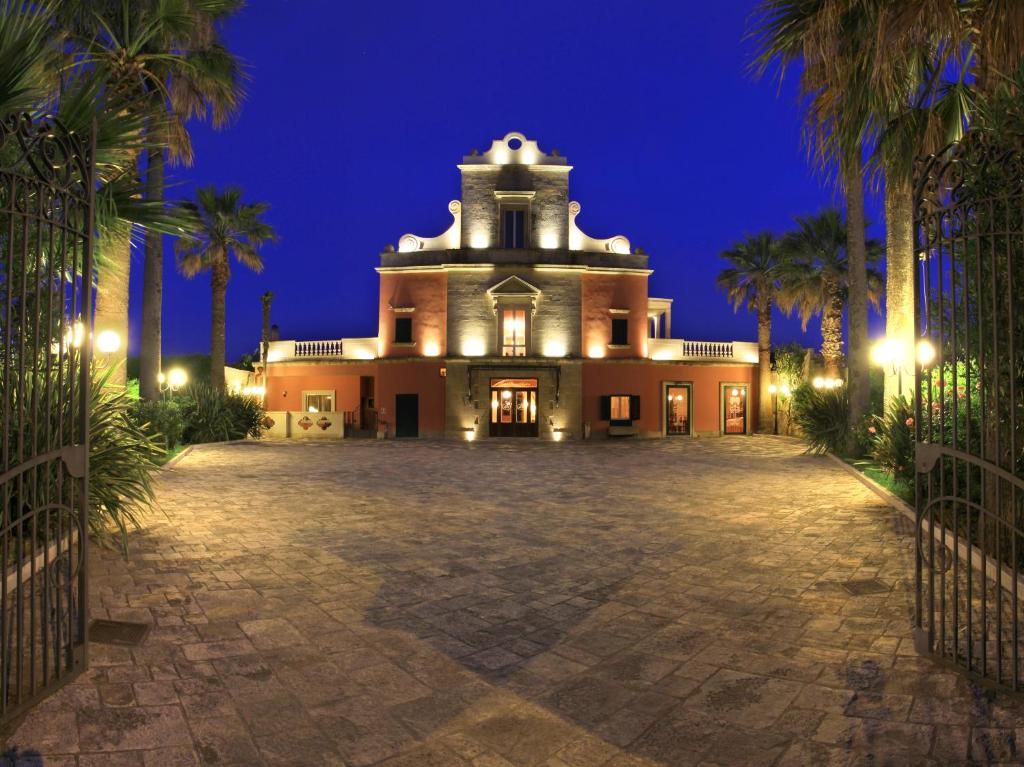 un grand bâtiment avec des palmiers la nuit dans l'établissement Villa Rosa Antico Dimora Storica, à Otrante