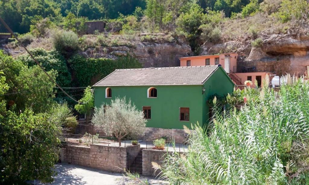 una casa verde en medio de una montaña en Refugio La Presa en Chulilla