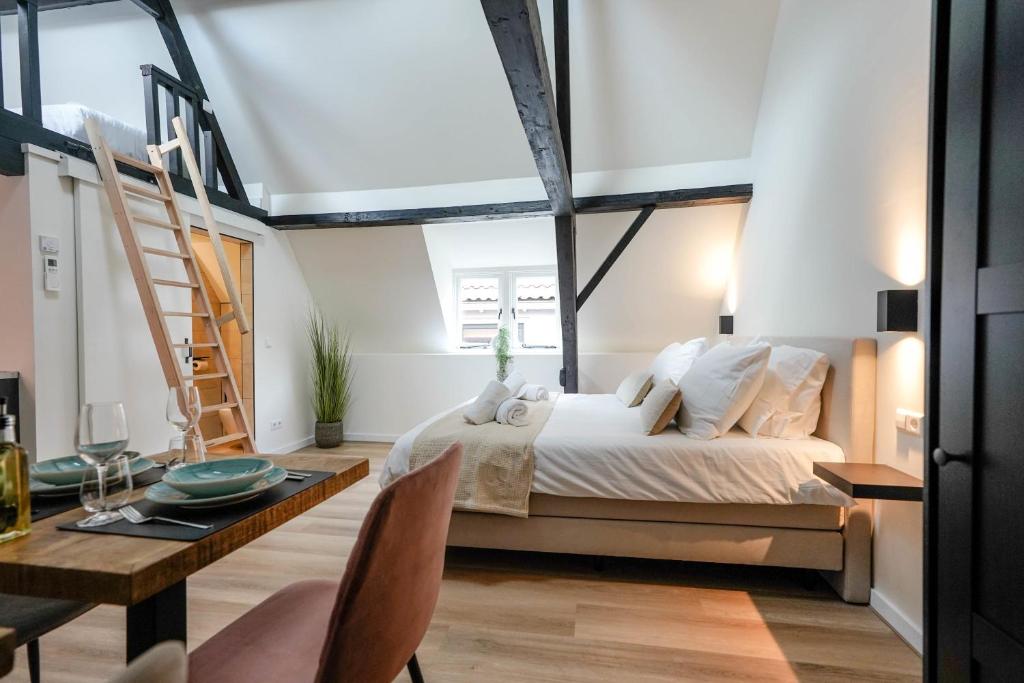 a bedroom with a bed and a desk and a ladder at Romantic 35m2 City Center Suite in Delft