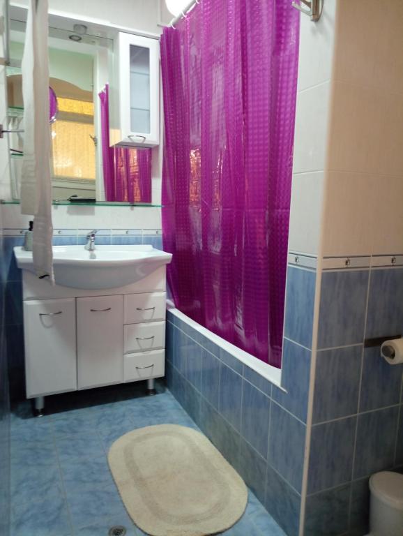 a bathroom with a sink and a pink shower curtain at Peace and quiet Kremasti in Kremasti