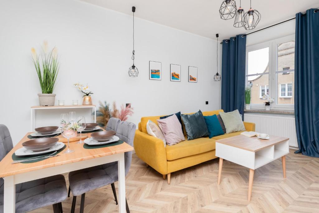 a living room with a yellow couch and a table at Old Town Apartment Garncarska by Renters in Gdańsk