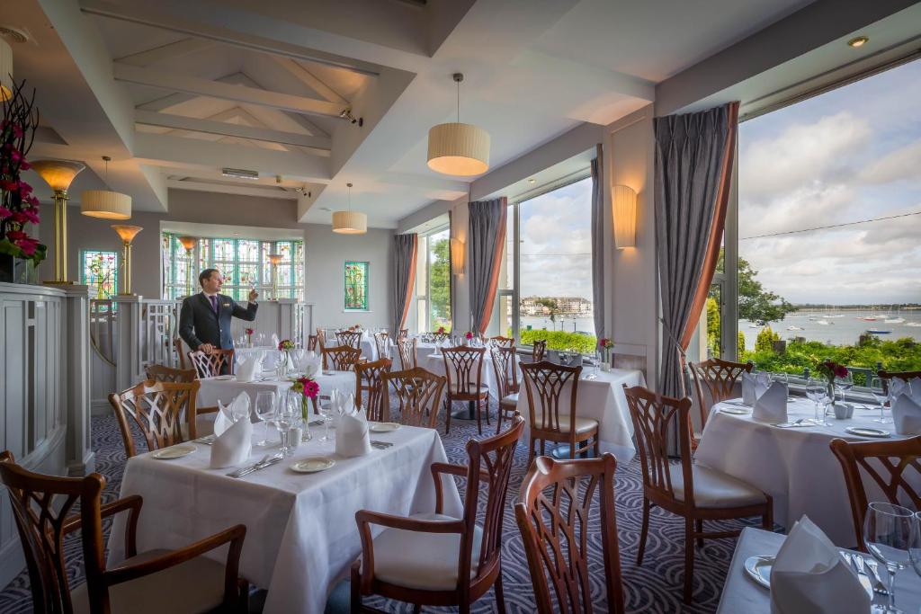 a restaurant with white tables and chairs and a man standing in the middle at Grand Hotel in Malahide