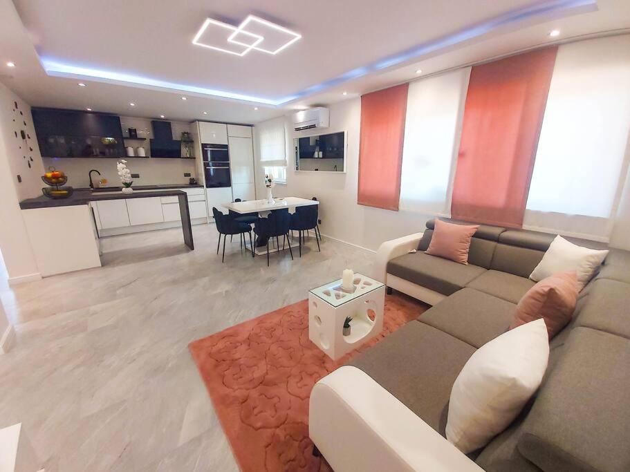 a living room with a couch and a table and a kitchen at Luxury two-bedroom apartment by the sea U KaLu in Postira