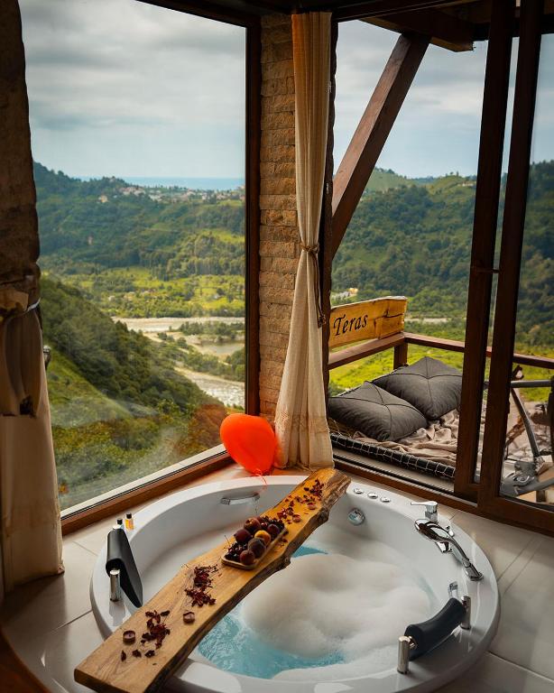 a bath tub in a room with a large window at Keyfi Teras Bungalov in Rize