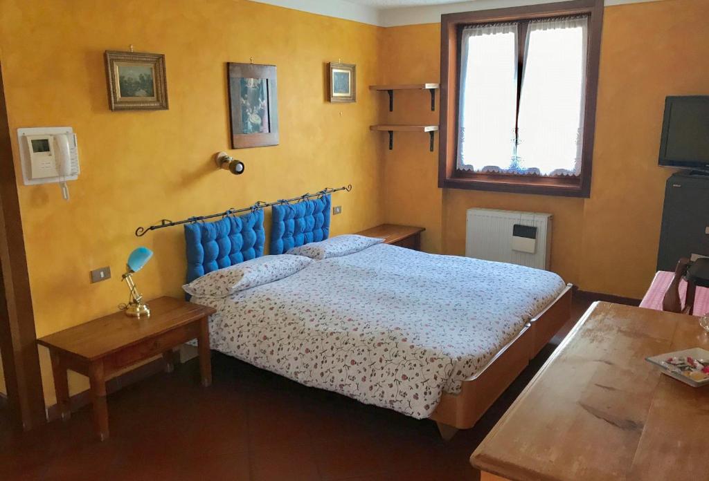 a bedroom with a bed and a table and a window at B&B La Quercia in Dimaro