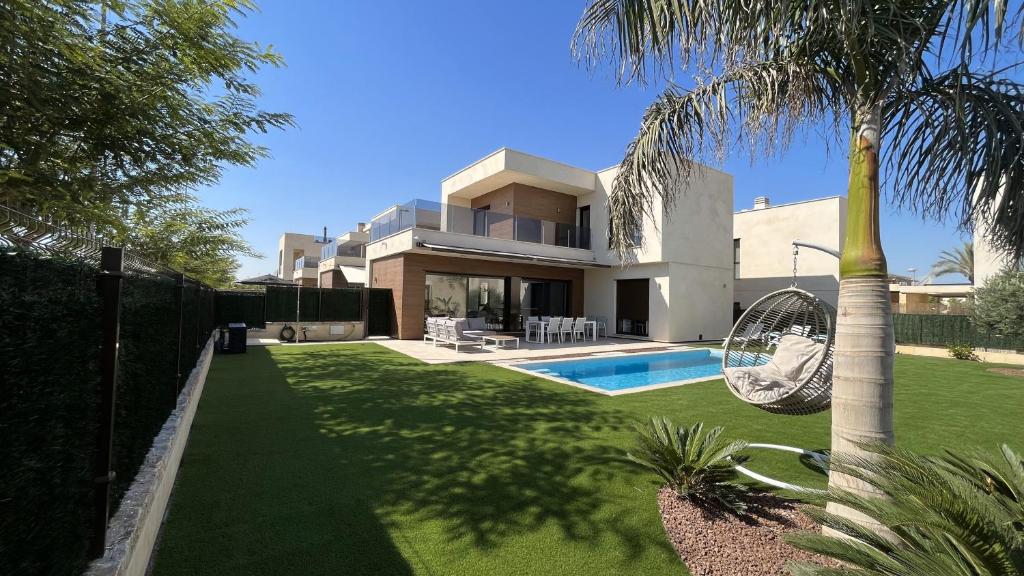 una casa con una palmera y un patio con un columpio en Villa with private heated pool - Roda Golf & Beach Resort, en San Javier
