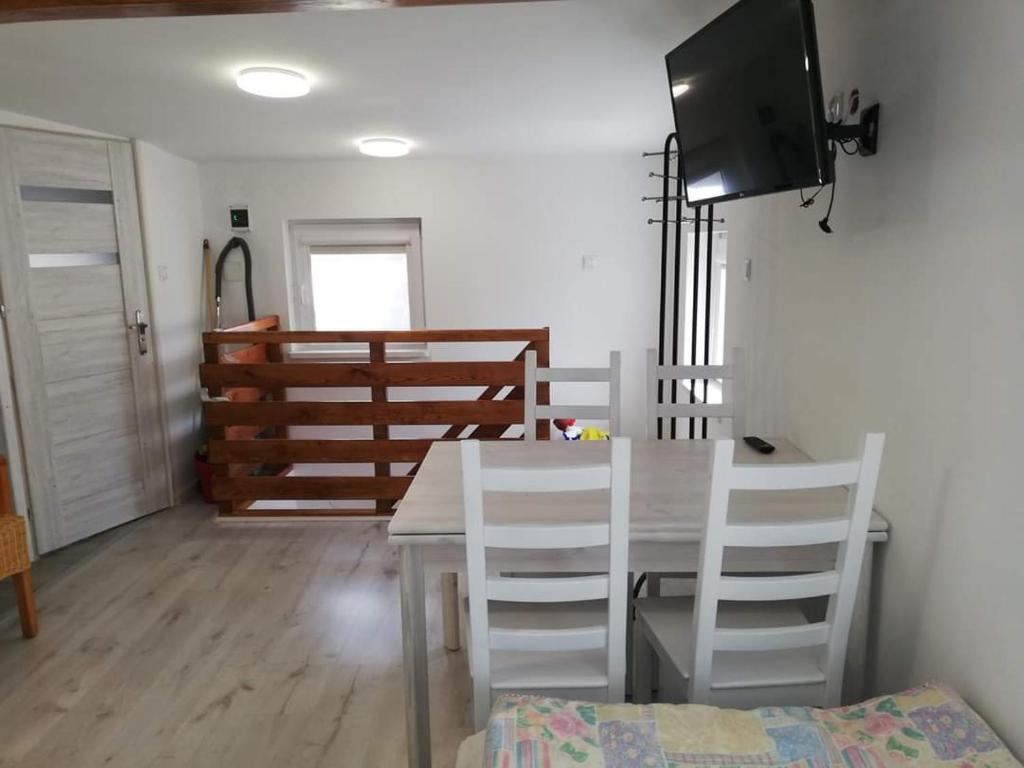 a dining room with a table and white chairs at Domek Augustowski in Augustów