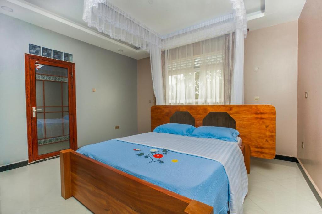 a bedroom with a large wooden bed with blue sheets at Malaika courts in Kampala