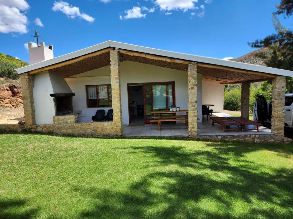 ein kleines Haus mit einer Terrasse und einem Grill in der Unterkunft Sipreslaan Selfsorg Gastehuis in Ladismith