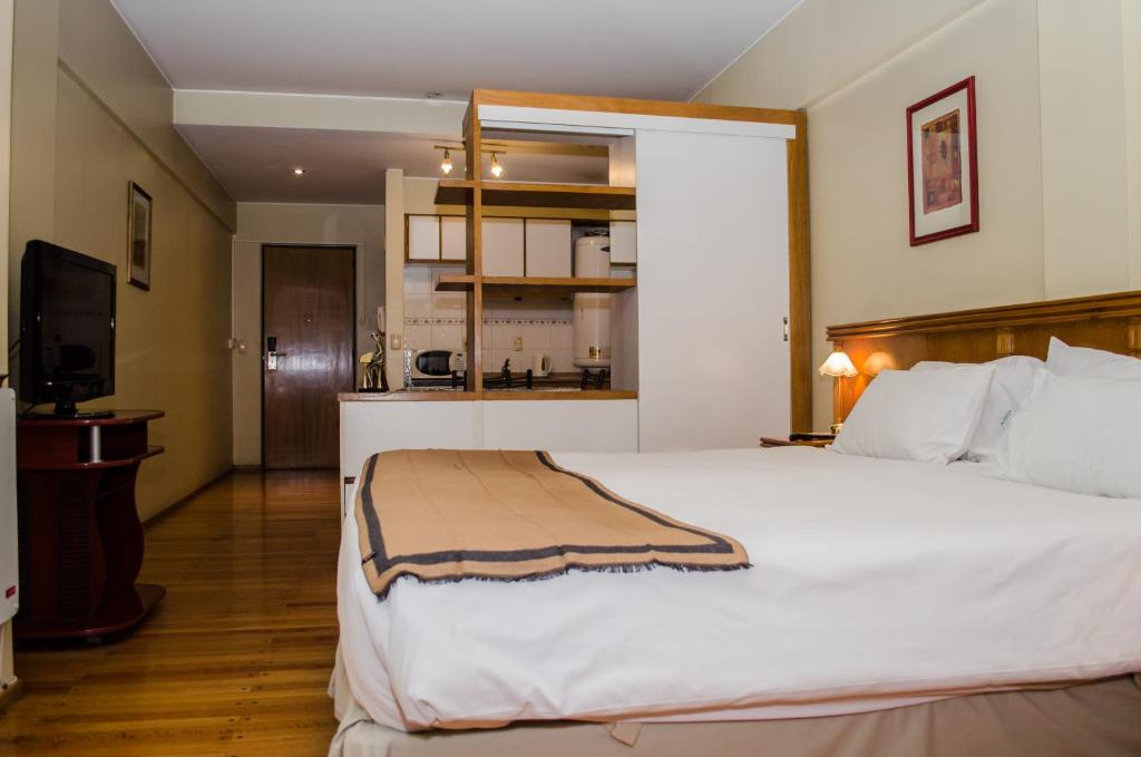 um quarto com uma grande cama branca e uma televisão em Altezza Apart Suites em Mendoza