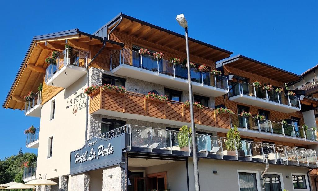 un edificio con balcones y macetas. en Hotel La Perla en Andalo