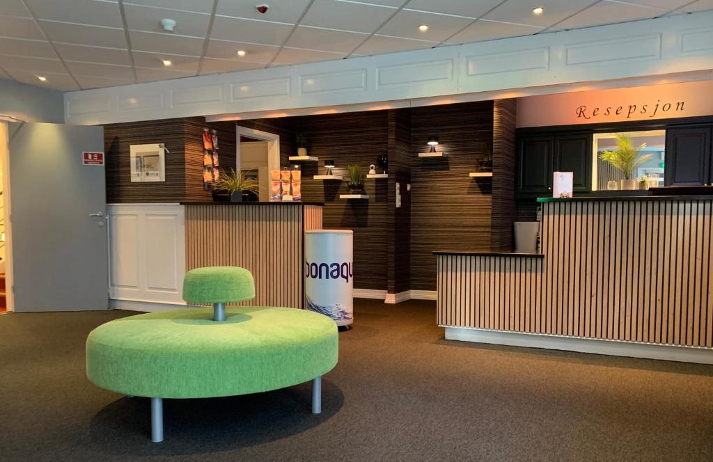 Bodø Hotel في بودو: غرفة بها كرسي أخضر في بهو الفندق