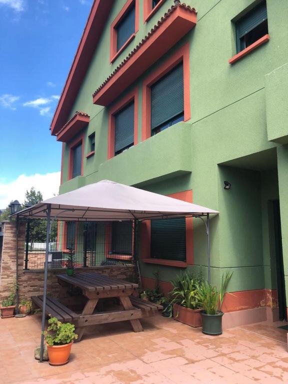 a picnic table with an umbrella in front of a building at Casa Mariva in Arriondas
