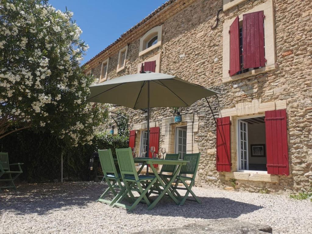 einen Tisch und Stühle mit einem Regenschirm vor einem Gebäude in der Unterkunft The Olive Press - Mon Lodge en Provence in Caromb