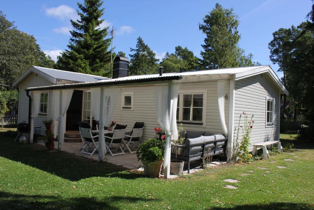 een wit tiny house met stoelen en een veranda bij Tofta Beach house in Tofta