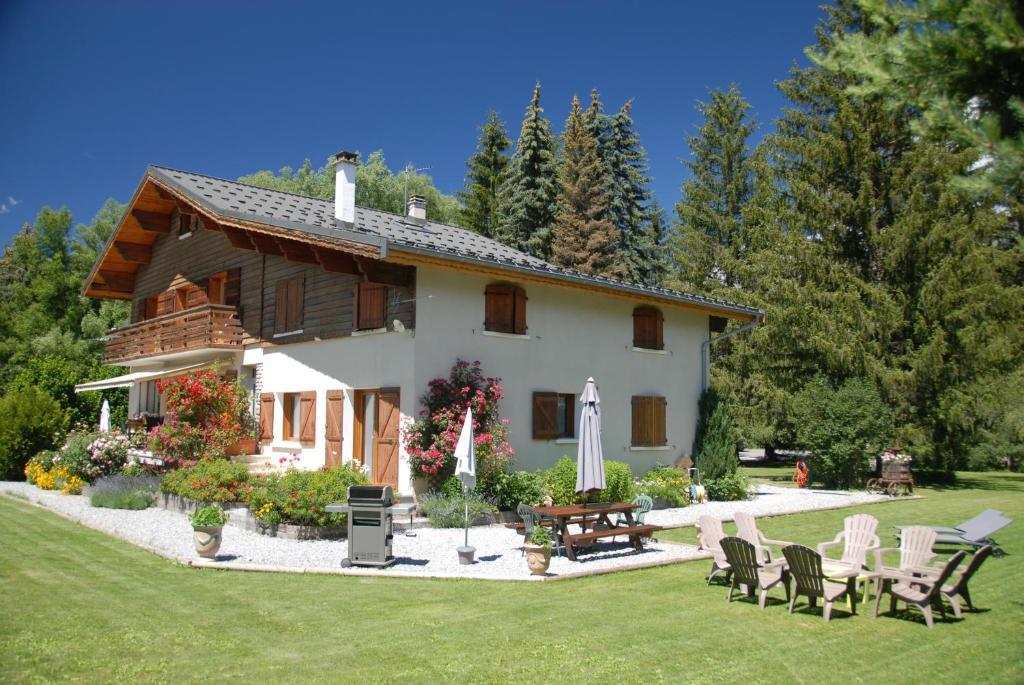 a house with a yard with chairs and a table at CHALET LES ECUREUILS in Barcelonnette