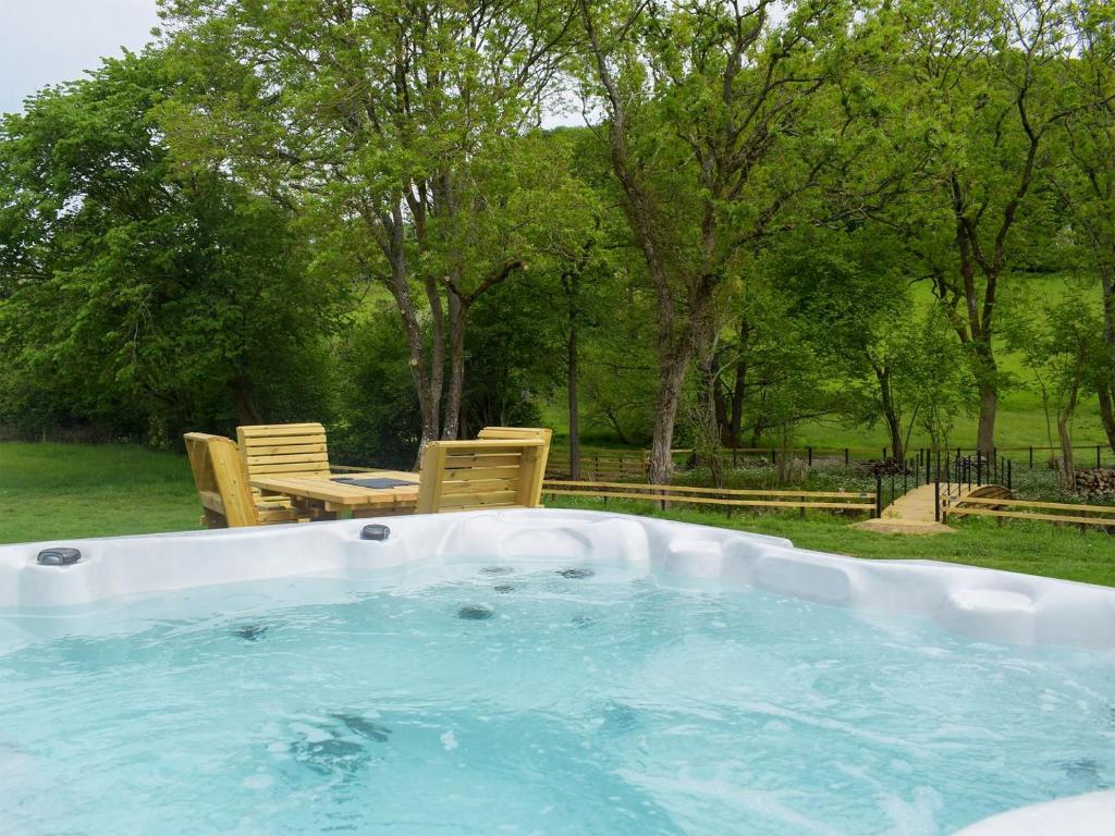 a hot tub in a yard with a table and chairs at Efyrnwy Pod Vip in Llanfyllin