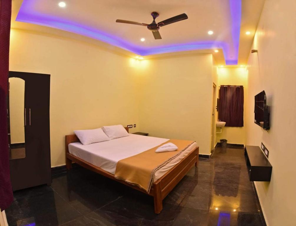 1 dormitorio con 1 cama y ventilador de techo en Sivakumar Paradise, en Mahabalipuram