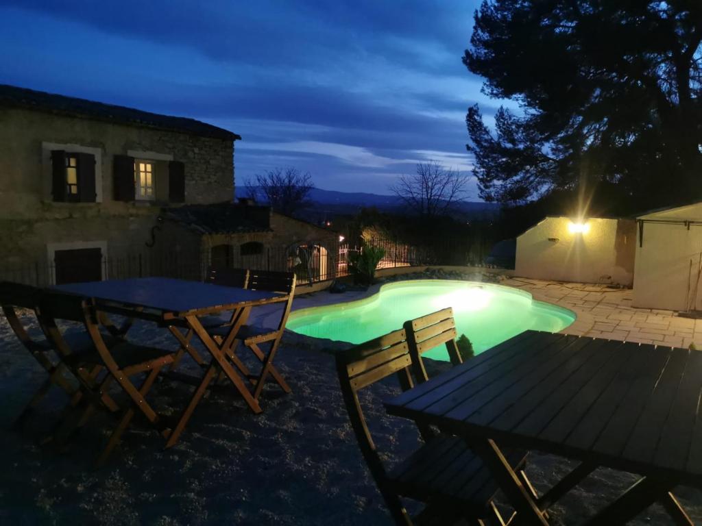 a swimming pool at night with a table and chairs at The Olive Press - Mon Lodge en Provence in Caromb