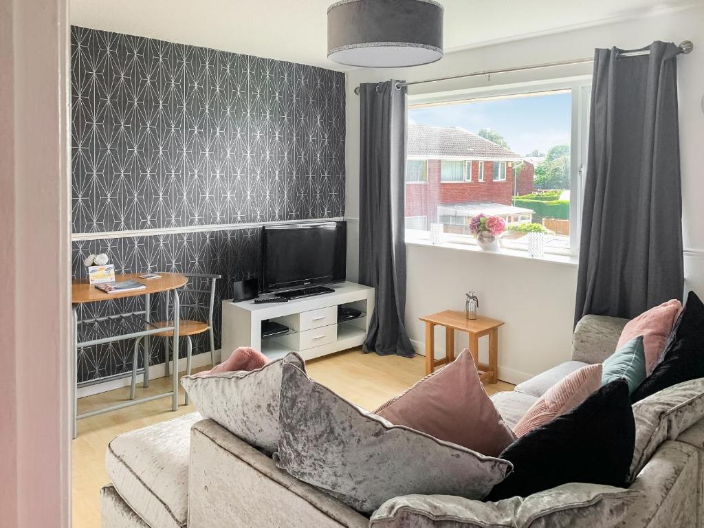 a living room with a couch and a television at Sunny Prestatyn Apartment in Prestatyn