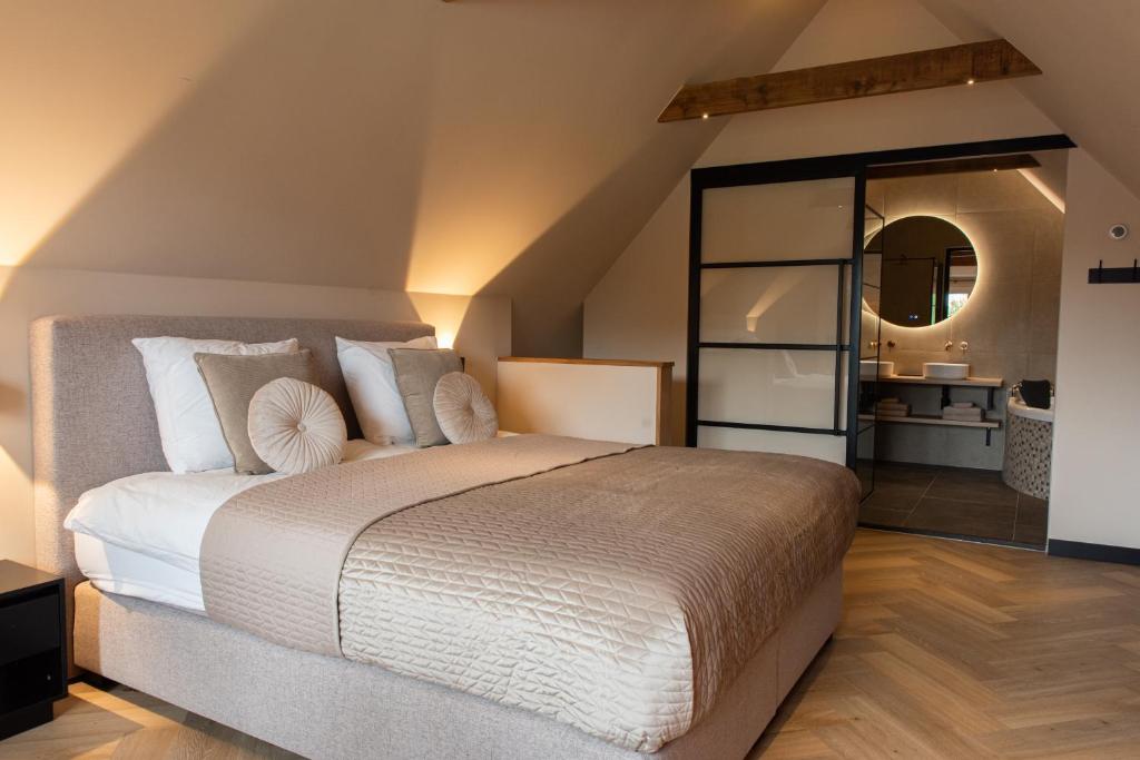 1 dormitorio con 1 cama grande y espejo grande en Bed & Breakfast Bellesza, en Oldeberkoop