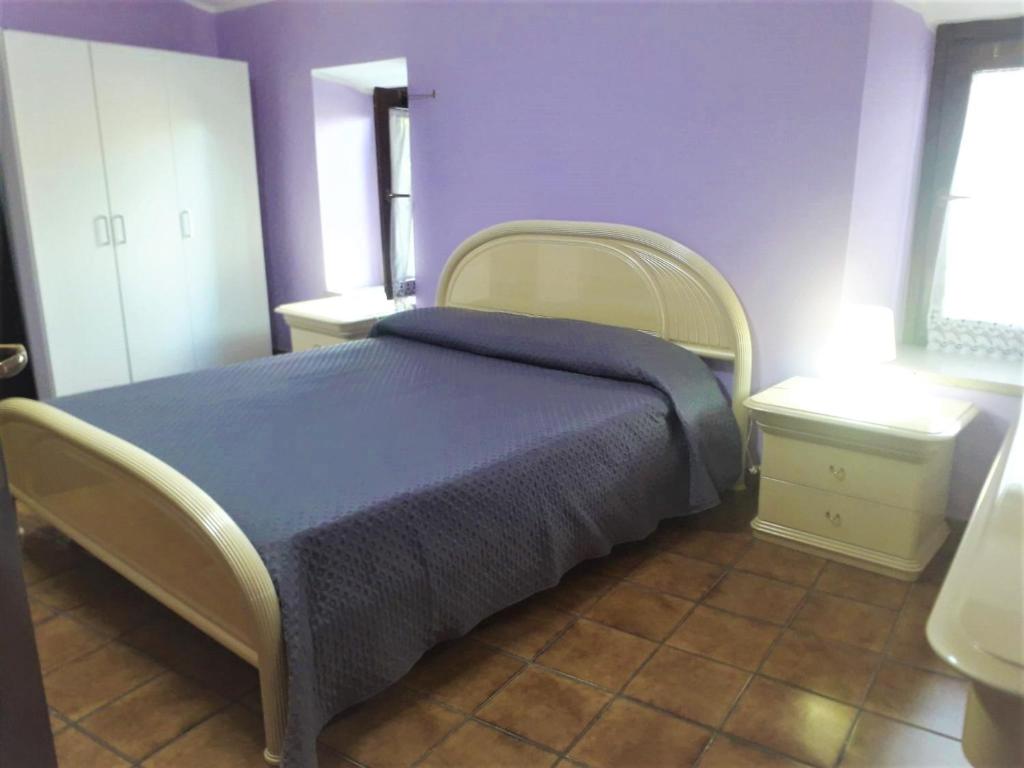 1 dormitorio con 1 cama con manta azul y paredes moradas en Casetta Santa Maria, en Subiaco