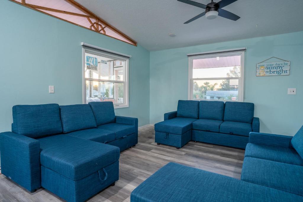 - un salon avec des canapés bleus et un ventilateur de plafond dans l'établissement Coral Cottage, à Weeki Wachee