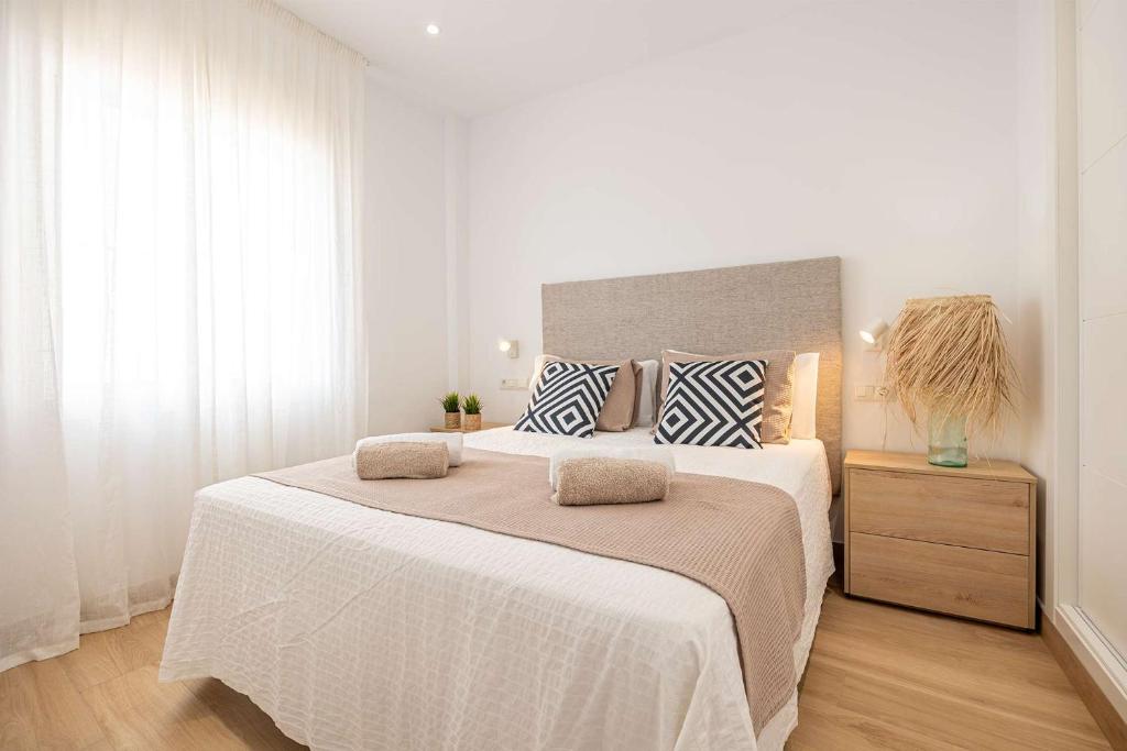 a white bedroom with a large bed with two pillows at APARTAMENTOS CARMEN in Maro