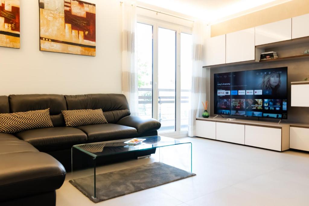 a living room with a leather couch and a tv at Wonderful Apartament, Near The Lake in Lugano