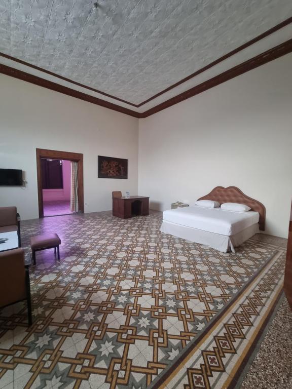 a bedroom with a bed and a floor with a rug at Hotel Candi Baru in Jomblang