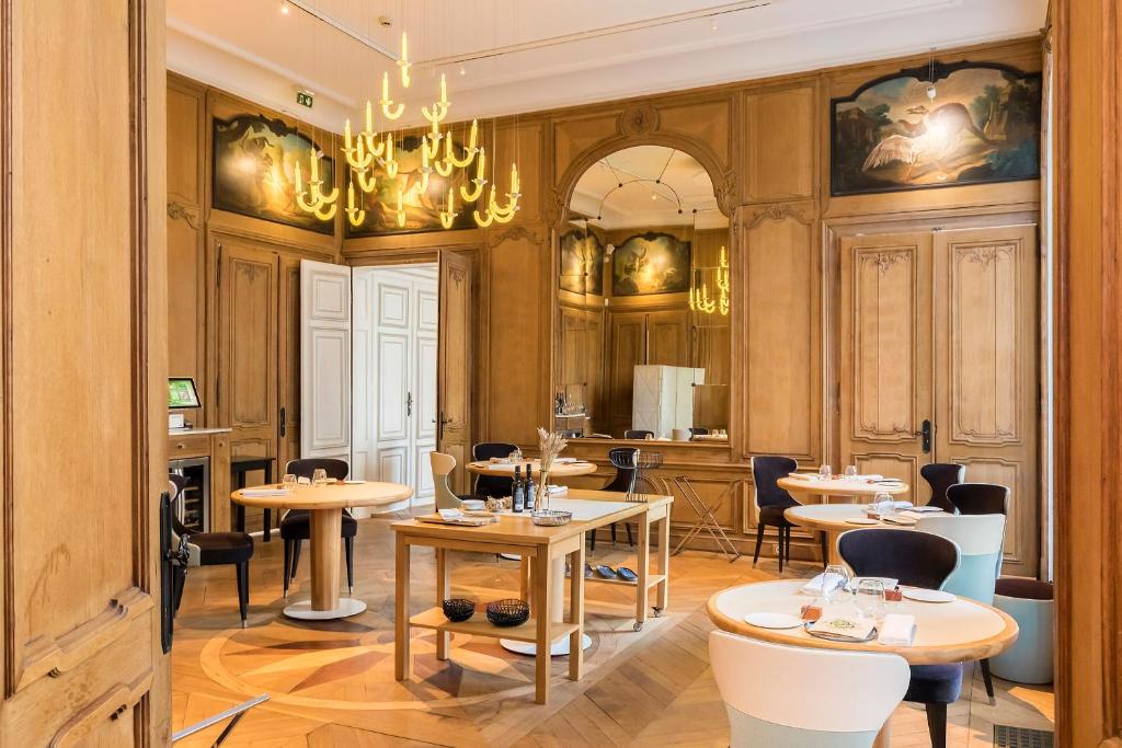 a restaurant with tables and chairs and a chandelier at Clarance Hotel Lille in Lille