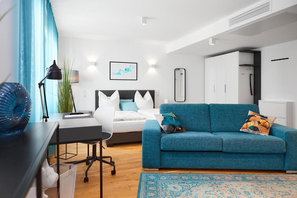 a living room with a blue couch and a bed at SERVENTO Boardinghouse in Erlangen