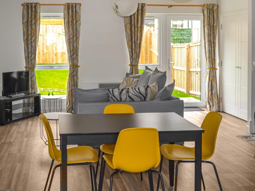 a living room with a dining room table and yellow chairs at Home Choi in Culloden