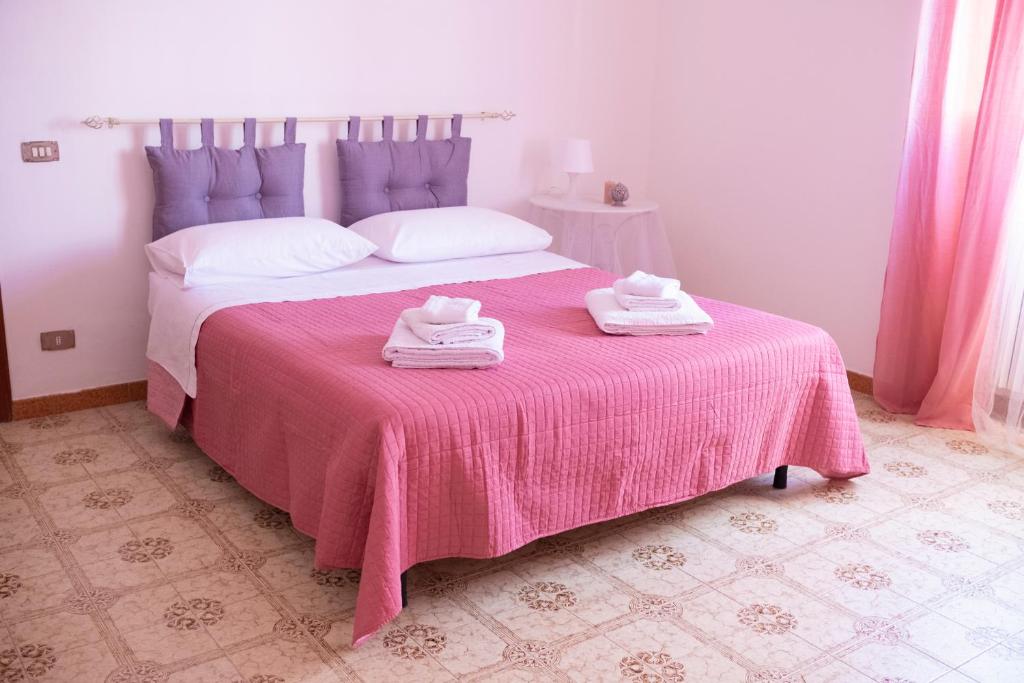 um quarto com uma cama rosa com duas toalhas em Casa vacanza “La Maison de famille” em Surbo