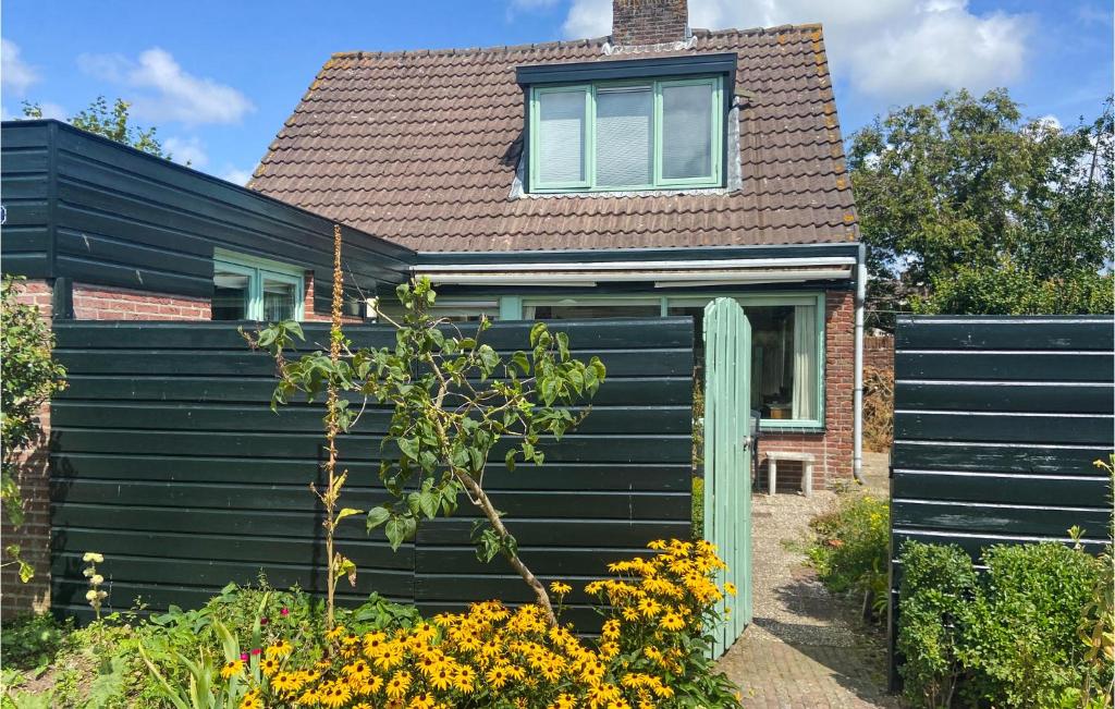 a black house with a black fence and flowers at 2 Bedroom Cozy Home In Noordwijkerhout in Noordwijkerhout