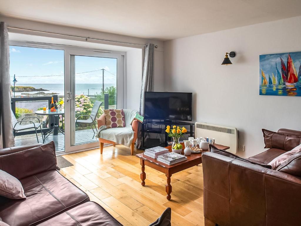 ein Wohnzimmer mit einem Sofa, einem TV und einem Tisch in der Unterkunft Harbour View in Cemaes Bay