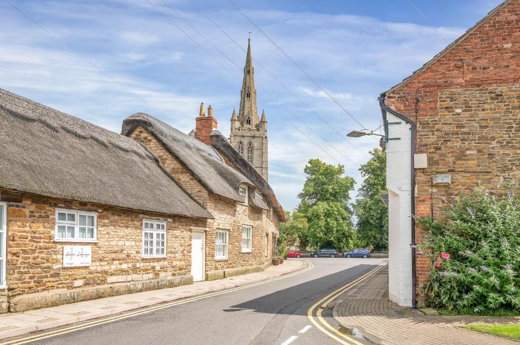 an empty street in a village with a church at The Limes - Beautiful Townhouse in Oakham in Oakham