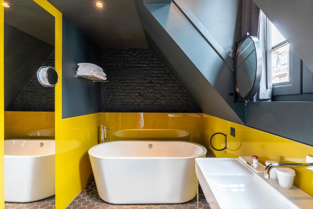 a yellow and blue bathroom with two sinks and a tub at Clarance Hotel Lille in Lille