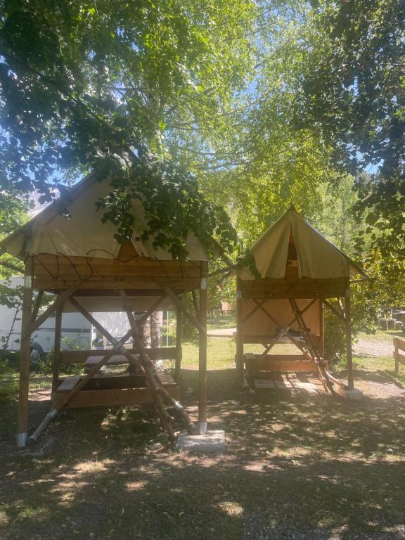 two shelters in a park under a tree at Camping chez Camille in Veynes