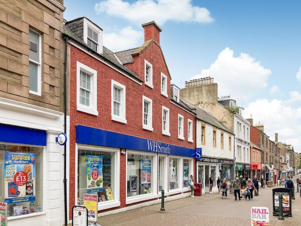 a street with buildings and people walking down a street at Apartment Three - Uk44286 in Arbroath