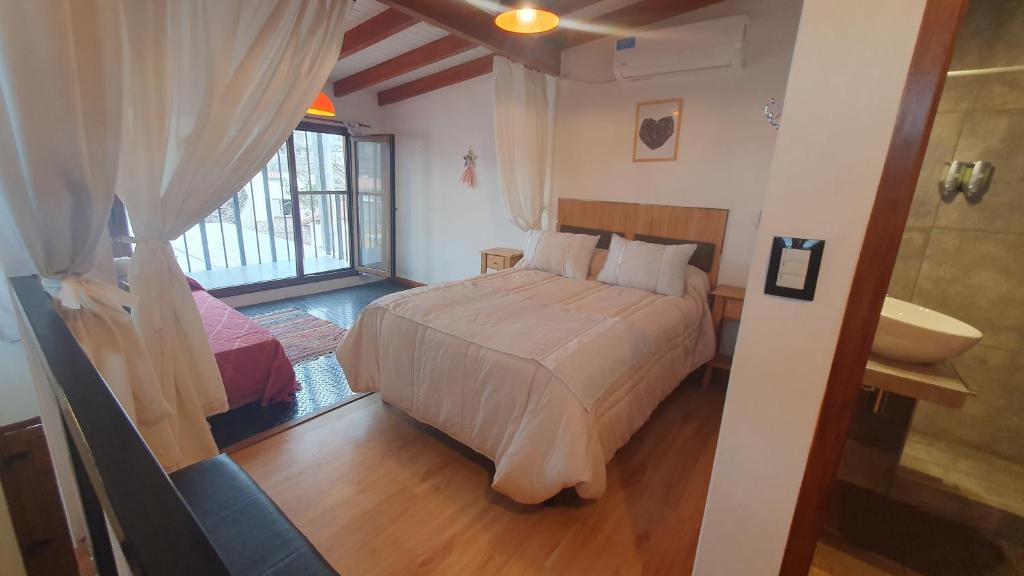 a bedroom with a bed and a bathroom with a window at Flor de Lis in Capilla del Monte