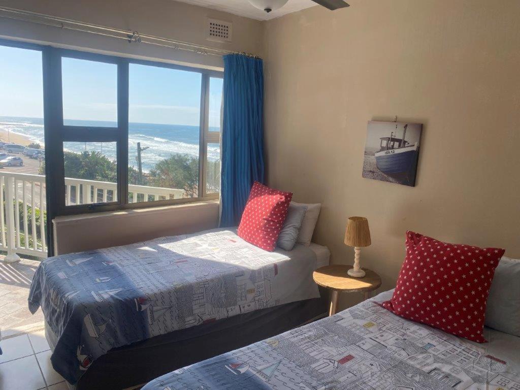 a bedroom with two beds and a large window at Umdloti Cabanas 32 Triplex in Umdloti