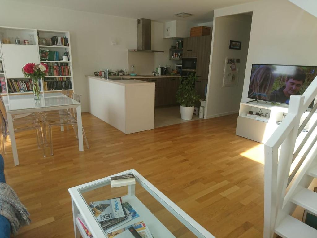 een woonkamer met een tafel en een televisie en een keuken bij Duplex lumineux Saint Ouen sur Seine in Saint-Ouen