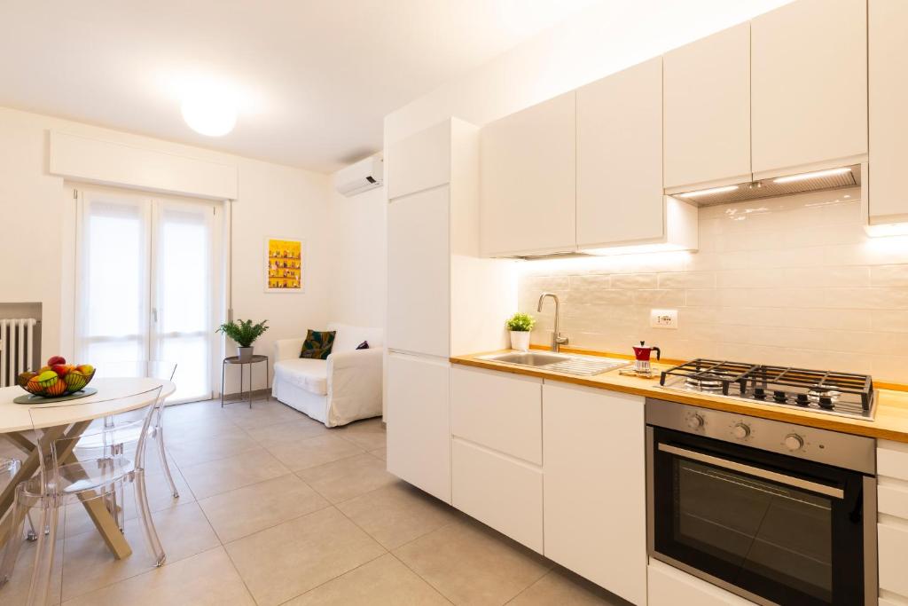 eine Küche mit weißen Schränken, einem Tisch und einem Esszimmer in der Unterkunft Brenta Top Floor - MM3 Yellow Line in Mailand