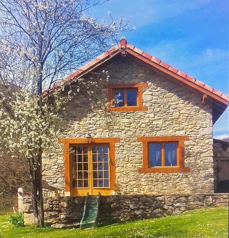 una casa de piedra con 3 ventanas y un árbol en Gîte Mourtis, en Nistos