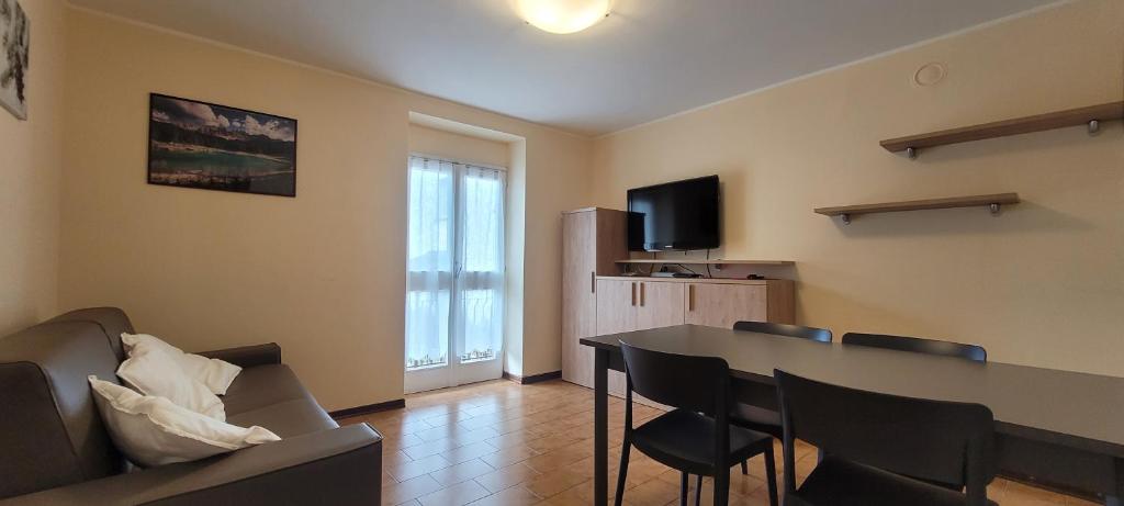 a living room with a table and chairs and a television at Il Giardino di Moggio in Moggio