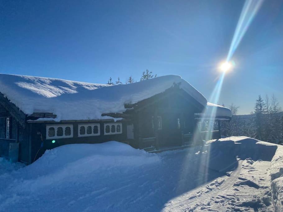 ein schneebedecktes Haus mit der Sonne dahinter in der Unterkunft TRYSIL - Koselig norsk fjellhytte in Nybergsund