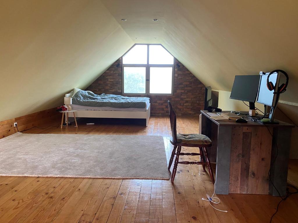 een zolderkamer met een bed en een bureau met een computer bij Sava River IN in Ledine